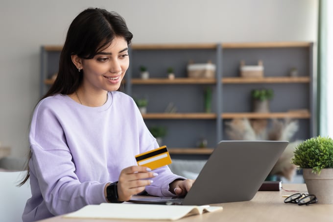 cheerful-millennial-female-using-computer-and-debi-2023-11-27-05-09-51-utc